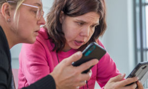 Kaksi naista tutkii yhdessä kännyköitä.