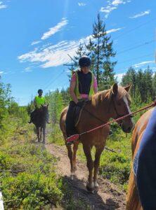 Kolme ratsastajaa maastossa.