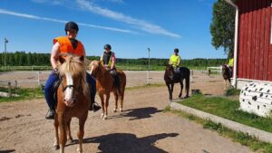 Ratsastajia tallin pihalla.