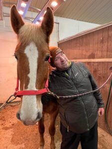 Mies ja hevonen seisovat vierekkäin ja katsovat kameraan.