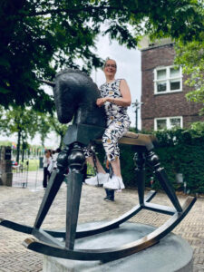 Nainen istuu suuren hevospatsaan päällä ja hymyilee.