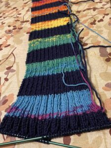 Neuleessa sinisiä, mustia, vihreitä ja keltaisia raitoja.