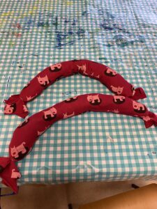 Kankaasta ommeltuja pitkulaisia koiran puruleluja. Kankaassa on koiran kuvia.